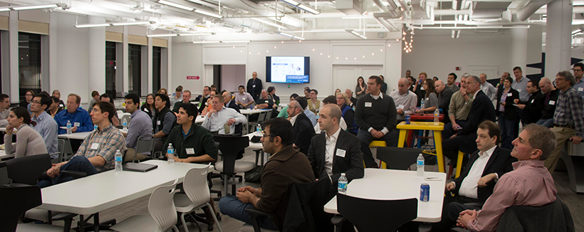 many people in a room sitting listening to someone present